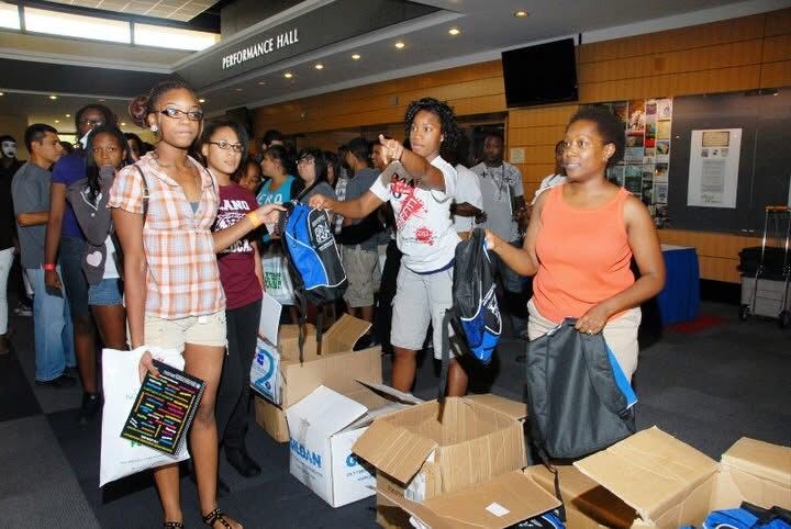 Volunteers handing out backpacks at a Keepin’ It Real! Youth Empowerment Summit